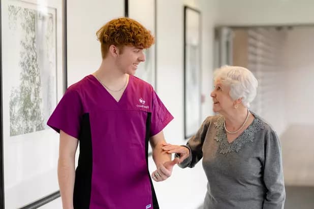 Chartwell Care staff walking along with the senior resident while holding her hand./ Le personnel de Chartwell Care accompagne la résidente âgée en lui tenant la main