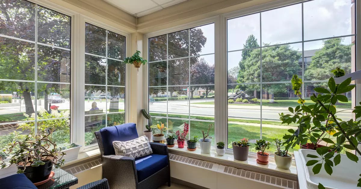 Bright sunroom with floor to ceiling windows at Chartwell Queen's Square Retirement Residence
