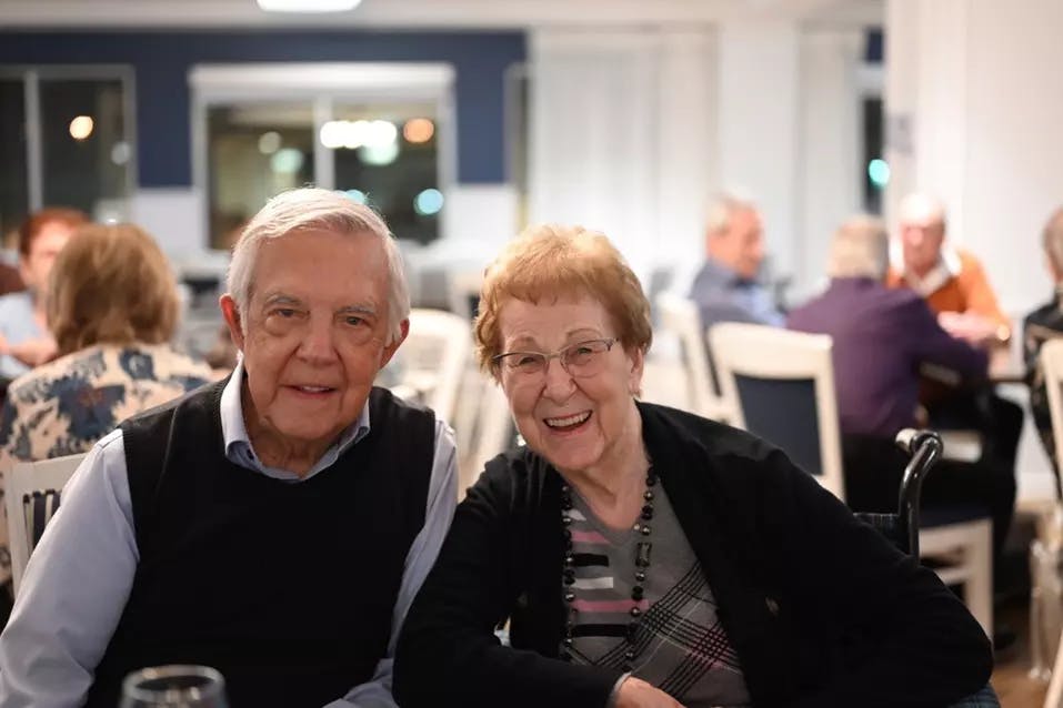Senior couple smiling in dining room. Couple de seniors souriant dans la salle à manger.  