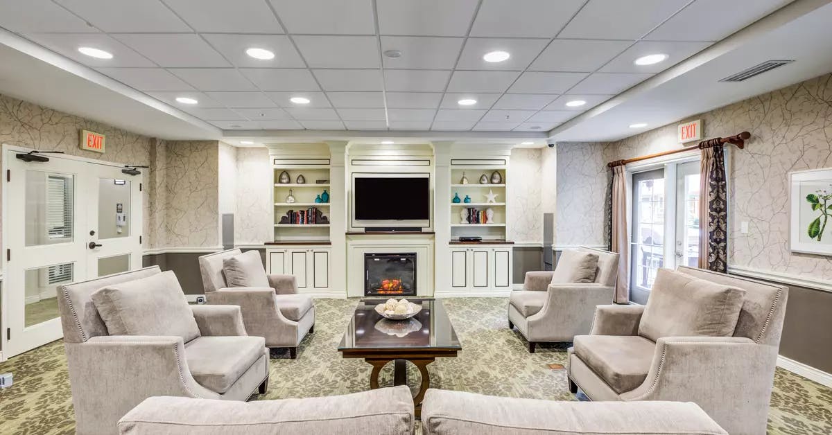 TV room with fireplace and comfortable couches at Chartwell Orchards Retirement Residence
