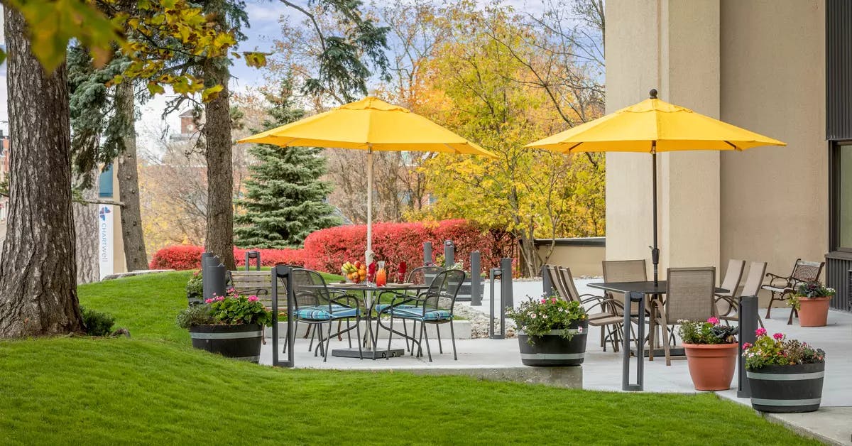 Walk out patio with greenspace and outdoor furniture at Chartwell Park Place Retirement Residence. 