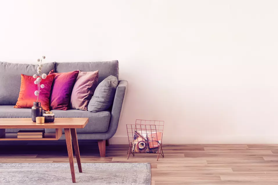 image of half of a living room showing a couch, coffee table and a book basket on the floor