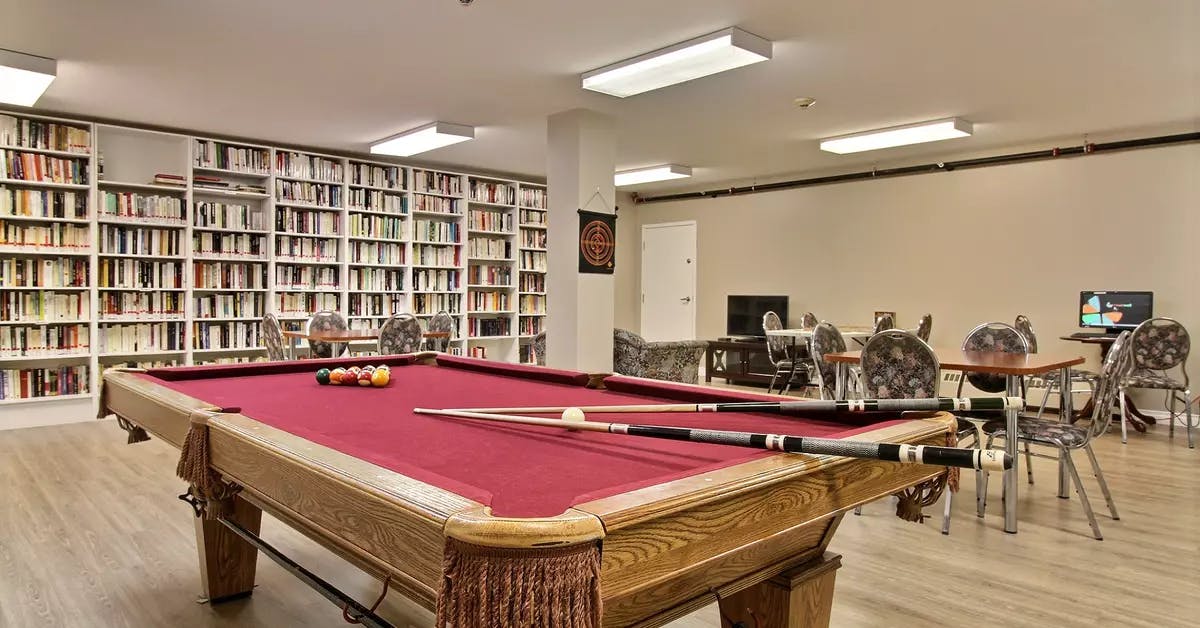 Bibliothèque avec table pour casse-tête et jeux et table de billard Chartwell Jardins de la Gare résidence pour retraités