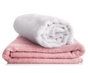 White rolled up towel on top of a folded pink towel