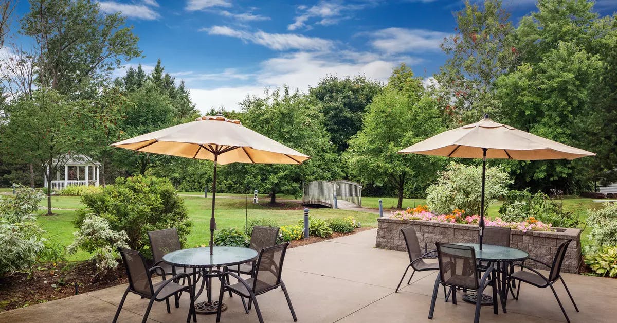 Gorgeous outdoor greenspace with walking paths and patio furniture at Chartwell Barton Retirement Residence.