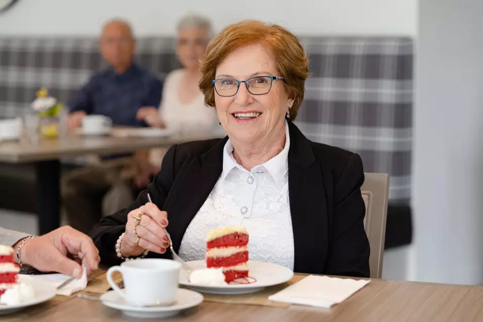 Senior woman eating cake. Femme âgée mangeant un gâteau.