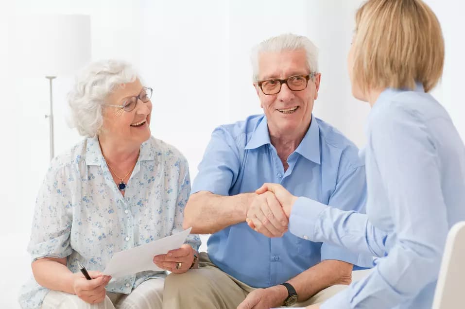 Happy senior couple sealing with an handshake a contract for the retirement / Un couple de seniors heureux scelle d'une poignée de main un contrat de retraite