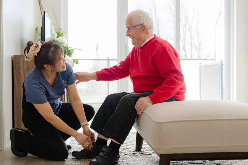 Chartwell Care Staff helping the senior resident wearing shoes / Le personnel de Chartwell Care aide la résidente âgée à porter des chaussures