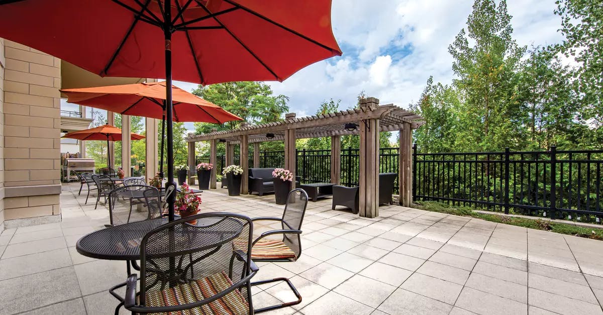 Chartwell Westmount's exterior patio with outdoor tables, chair and umbrellas
