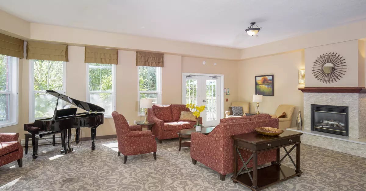 lounge with piano and fireplace at chartwell jackson creek retirement residence