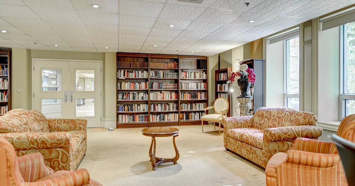 Salon commun avec bibliothèques remplies de livres Chartwell Domaine de Bordeaux résidence pour retraités