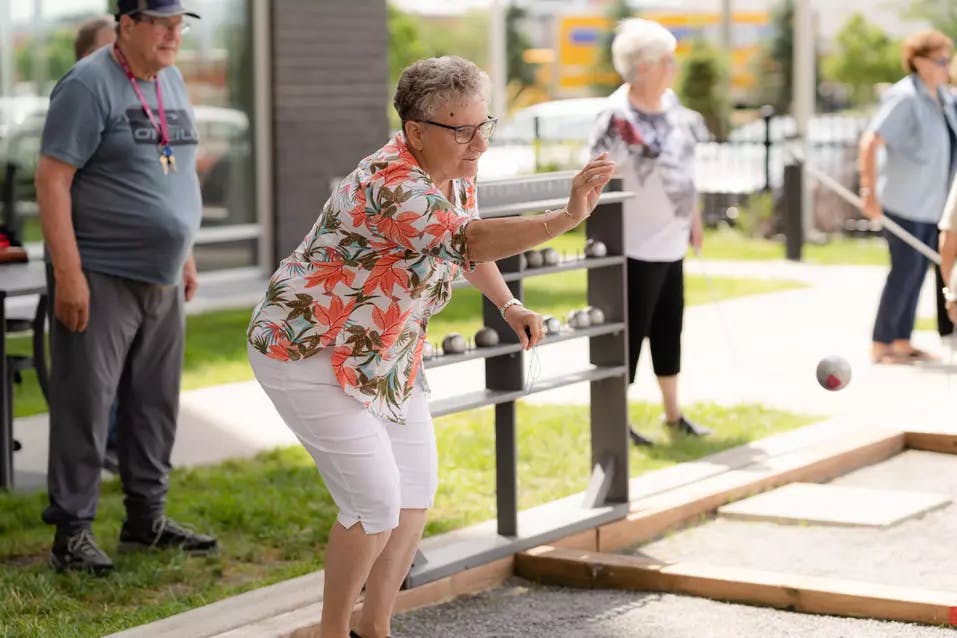 Senior resident throwing Bocce ball while the other look over her