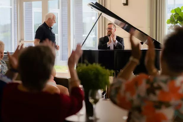 Senior residents applauding after a piano performance by a resident.
