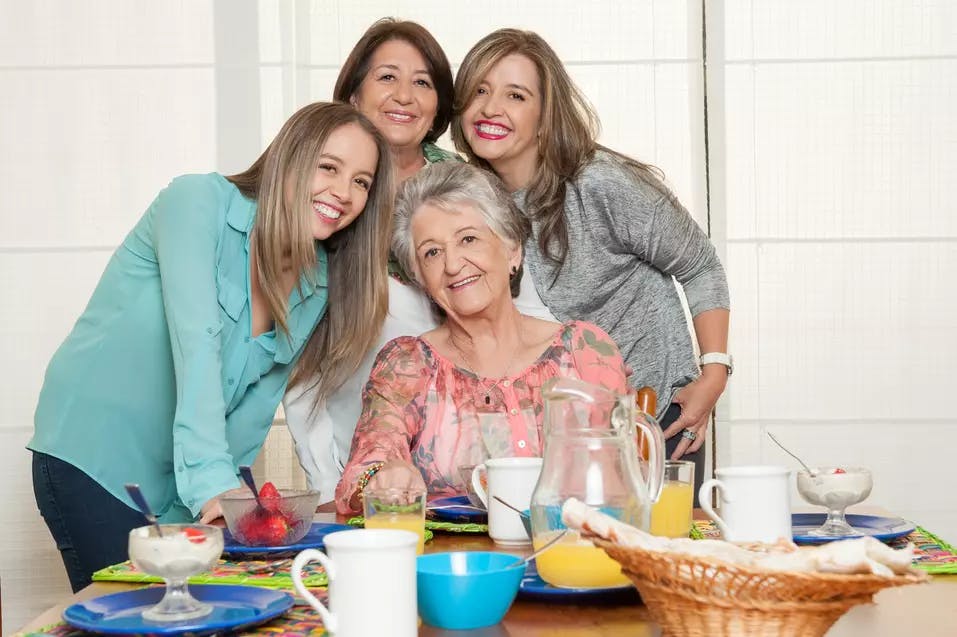 Senior woman and her three daughters gathered in front of the lunch table / Femme âgée et ses trois filles réunies devant la table du déjeuner
