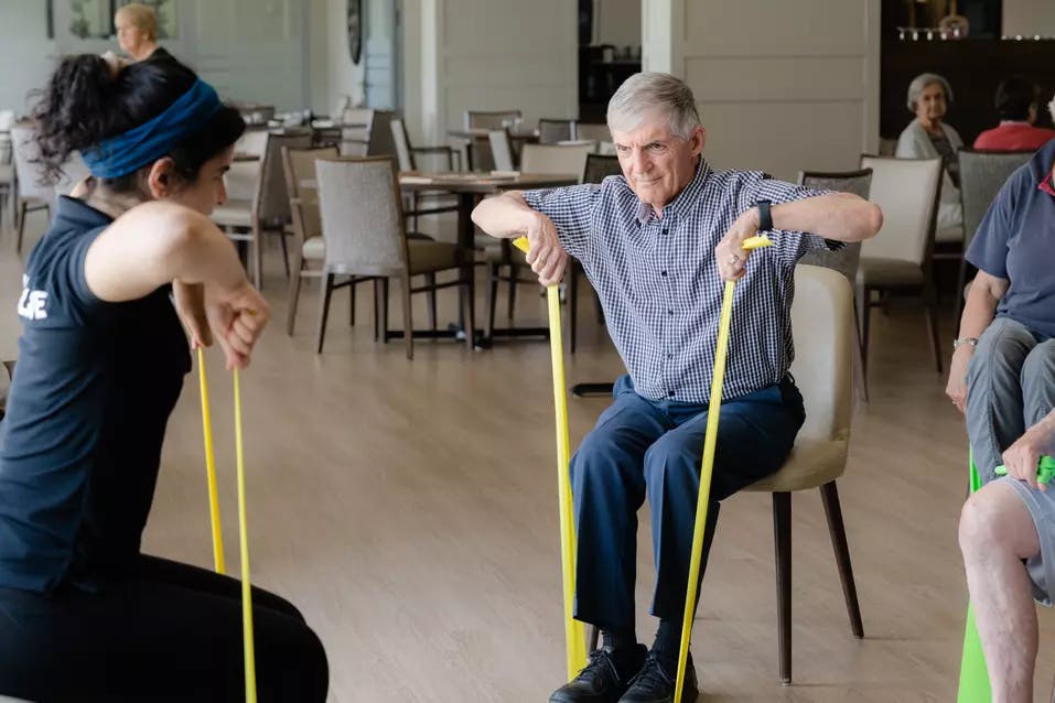 Senior resident exercising on chair with the instructor