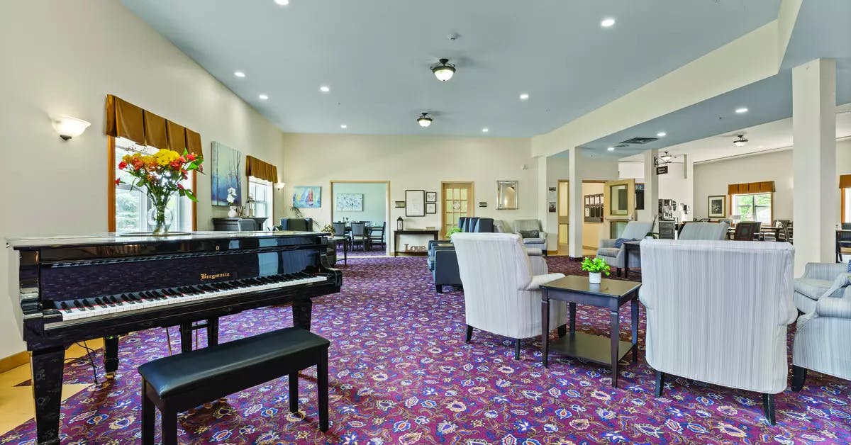 Lounge with piano and entertaining space at Chartwell Barton Retirement Residence.