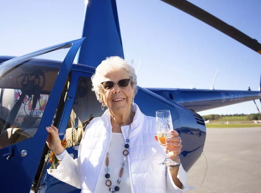 Senior woman drinking near helicopter. Femme âgée buvant près d'un hélicoptère.